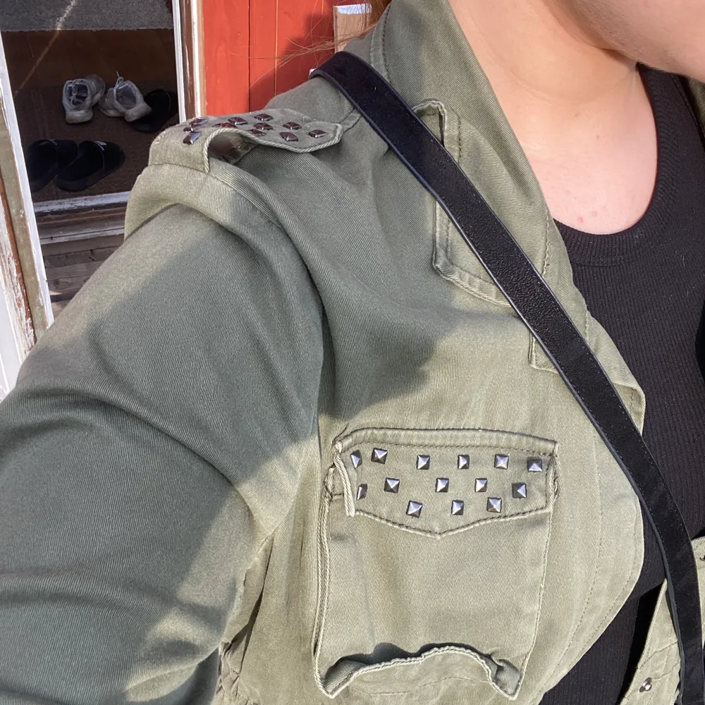 En rätt tunn militärgrön jacka med silvriga ”nitar”. Jackor.