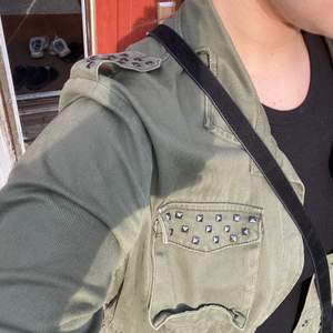 En rätt tunn militärgrön jacka med silvriga ”nitar”