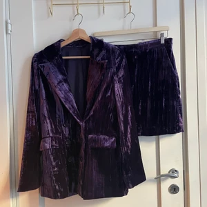 Kostym med kjol i sammet från &other stories - Mörklila kostym i ribbad sammet med minikjol. Kavajen är dubbelknäppt och i storlek 38. Kjolen är i storlek 42 men väldigt liten i storlek.   Använd endast två gånger! 