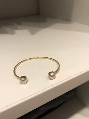 Säljer detta armnband från Caroline svedblom  som är helt nytt, guldigt med vita pärlor 