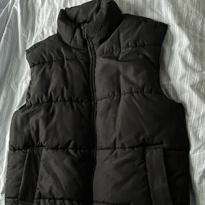 Dunväst svart - Tjock väst som håller värmen både till Höst/Vinter/Tidig vår,  Två fickor Den är i storlek M-L Använd ca 2-3 gånger och säljs enbart för det inte är min stil längre:) Passar bra med stickade tröjor och Hoodies!