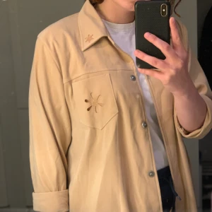 Vintageskjorta med blommdetaljer  - Skjorta i tjockare material. Funkar både som topp och som något att dra på sig över sina kläder en sen sommarkväll