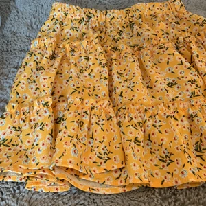 Volangkjol - Jättesöt gul volangkjol i storlek 140💛 Rätt så kort och har resår i midjan, den har vitblåa blommor på sig och gröna blomblad!💛 pris kan diskuteras. Frakt: 59 kr💛