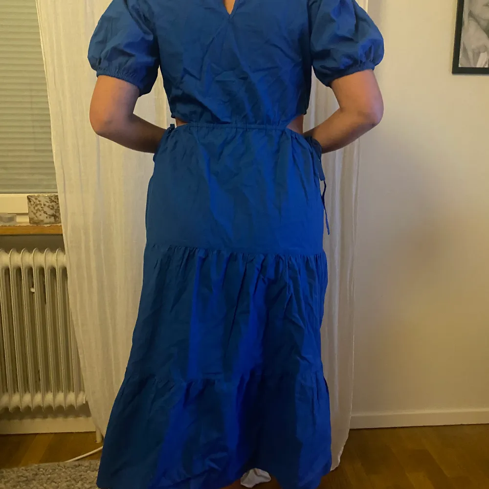 Koboltblå midiklänning med utskurna detaljer i sidan. Nyskick - prislappen kvar . Mekot.