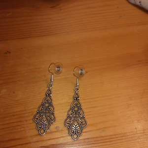 Örhängen med hänge silverfärgade . - Helt nya och oanvända örhängen med hänge silverfärgade ,ej silver .nickelfritt .EGEN DESIGN .hämtas alt skickas .portofritt Swishbetalning tillämpas .