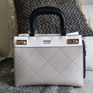 Guess västa katey - Svart/ beige väska från guess 6 mån gammal, bara använd ett par ggr. Flera fack inuti