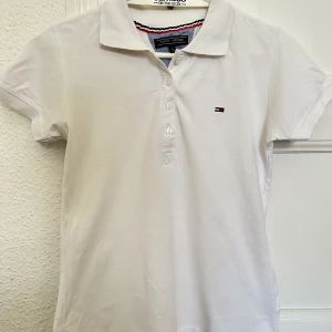 Vit Tommy Hilfiger Polo - Bra skick, nästa aldrig använd. Liten i storlek så närmare en M.