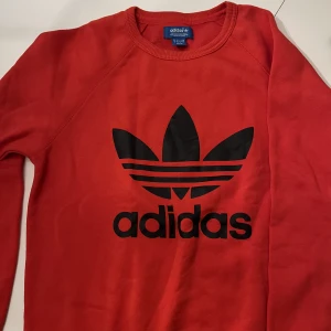 Sweatshirt - Säljer denna röda fina sweatshirt från Adidas. Enbart använd en enda gång. Det är en M!