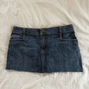 Jeanskjol - Snygg blå jeanskjol med coolt spänne där bak. Midjemått: 80cm och den är 30cm lång. Hör av er vid frågor!