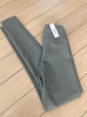 Sanne Alexandra Faux leather leggings S - Helt nya och oanvända faux leather leggings i storlek S från Sanne Alexandra Stockholm. Mjuka och jättesköna, med flossad insida och hög midja. Grå färg med tags kvar. Nypriset är 849:-