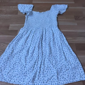 Klänning  - Säljer en vit klänning med ljusblå blommor, hör av dig om du är intresserad!