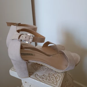 Beiga klackar - Beige/nude klackskor i mockaimitation. Passar perfekt till bal eller andra festligheter! Är i storlek 41 men passade mig som vanligtvis har storlek 40. Använda endast en gång.