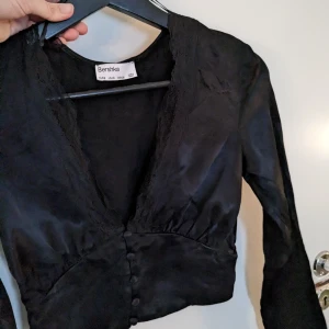 Blus i S - Svart blus i glansigt material från Bershka i storlek S. 