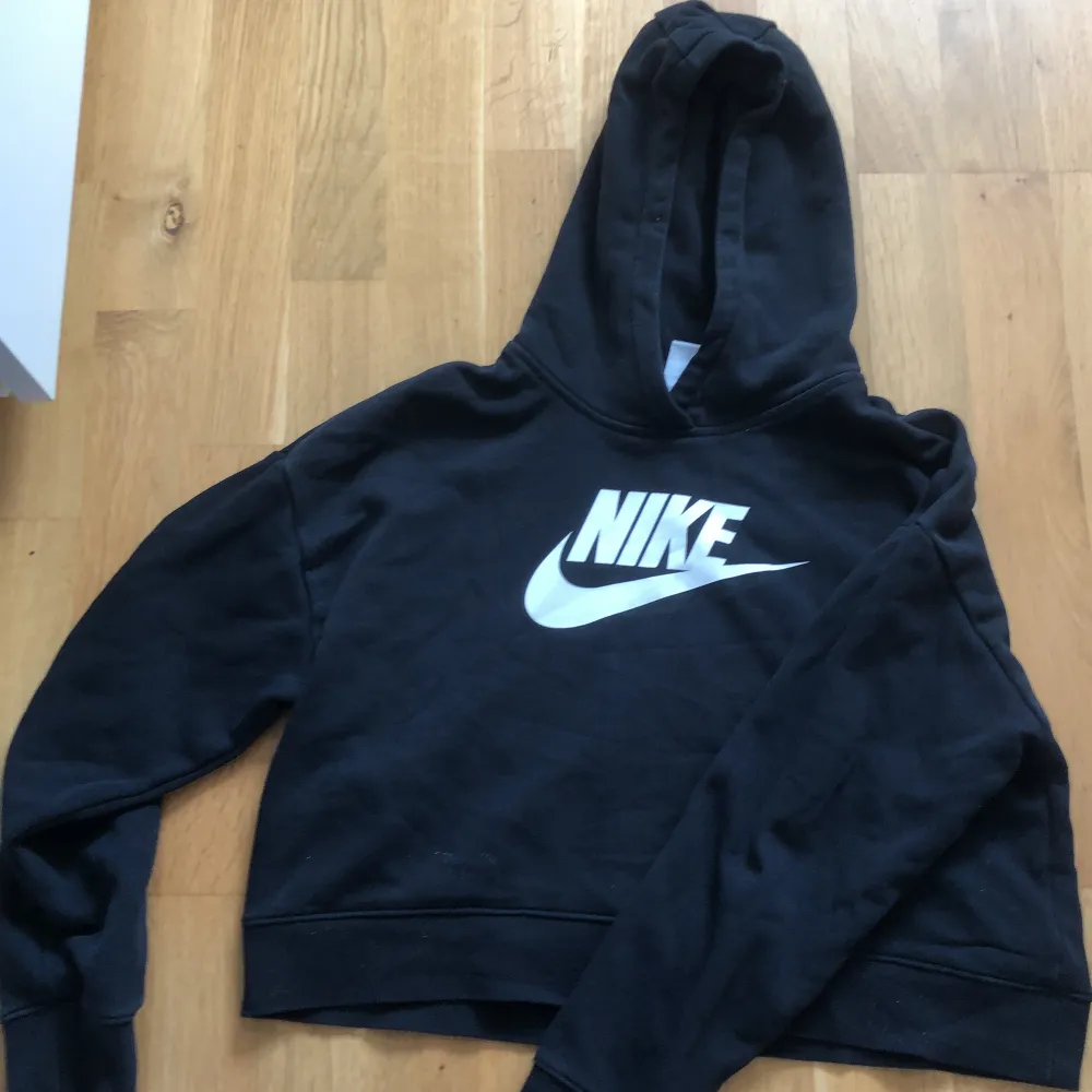 En svart kort hoodie ifrån Nike. I storlek L som motsvarar ungefär 146/152. Tröjor & Koftor.