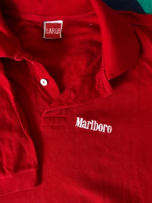 VINTAGE Marlboro Piké - Lägg vantarna på denna! En vintage Marlborotröja i storlek Large (sitter fint på mig som brukar ha medium så den är nog lite mindre än standard large). Den här fräna pikén är såvitt jag vet praktiskt taget oanvänd, har legat i en låda på vinden.