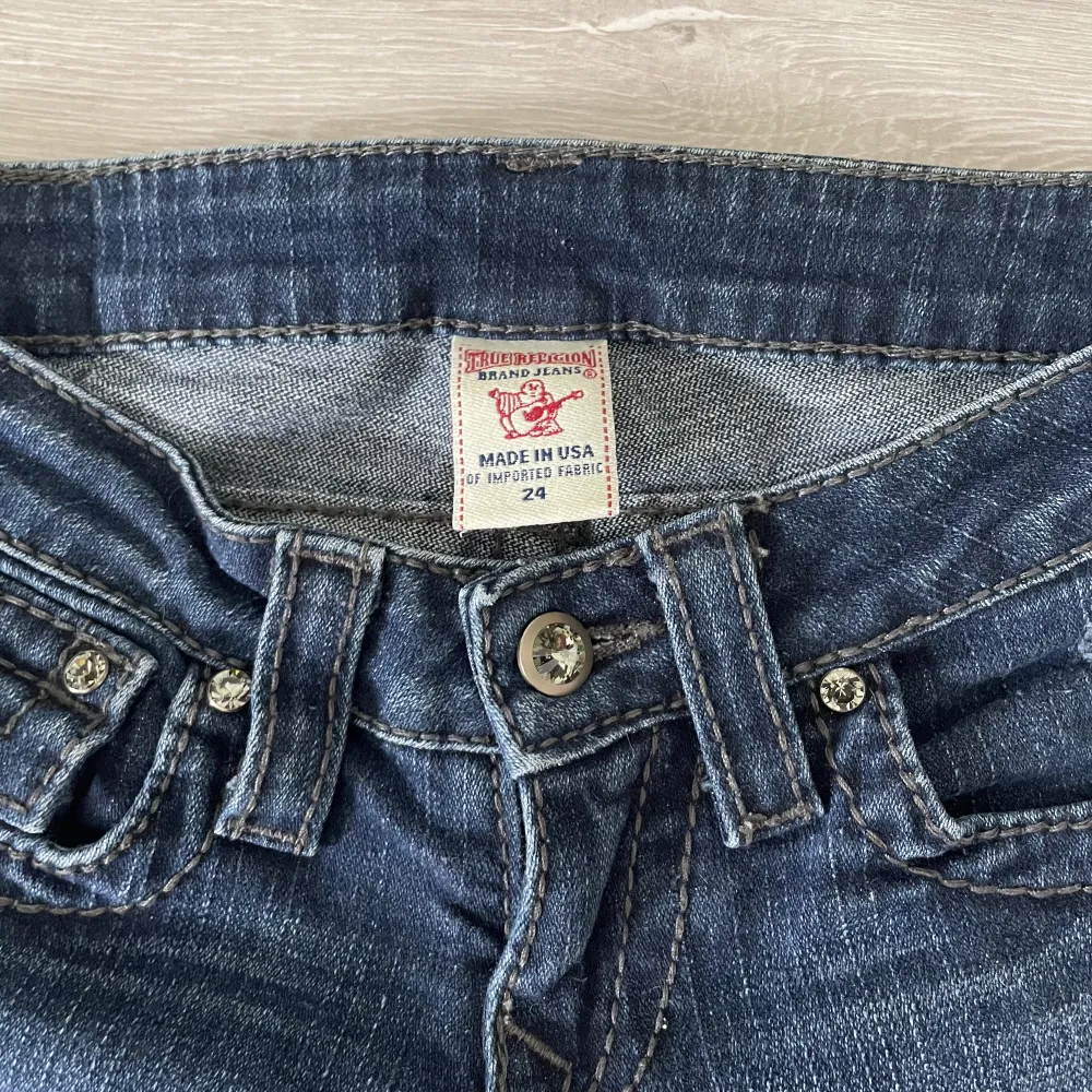 Snygga True Religion jeans i low waist och straight leg modell💙 Bakfickor med knappar och lite slitningar på framsidan🌟 Markerad w24, se mått: 37cm platt midja (kan stretchas till ca 39cm), 18cm midjehöjd, 85cm innerbenslängd💫 Skriv för fler bilder💓. Jeans & Byxor.
