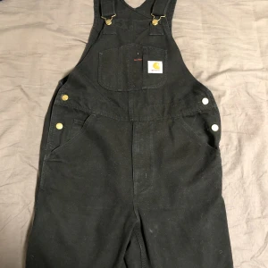 Carhartt hängselbyxor  - Svarta carhartt hängselbyxor! Passar perfekt på mig som är runt 170! Fråga om mer bilder om de behövs! 