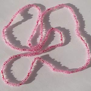 Halsband gjort med rosa glas och plast pärlor med elastisk tråd.