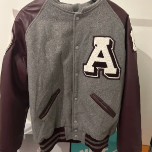 Varsity jacket  - Säljer en vinröd varsity/college jacka som är i fint skick och väldigt snygg den har en stor kappa på ryggen men som går att vika in som jag visar på bilden.  Jackan är i storlek L men sitter mer som M.  Köpt på beyond retro Skriv för mer bilder&frågor.