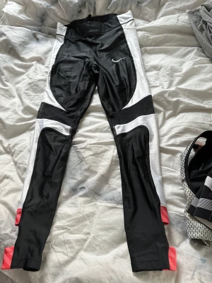 Nike träningstights - Nike träningstights som är använda ett par gånger. Dom har me ficka på sidan av benet så man kan ha mobilen i. Tyvärr har dom gått sönder vid det rosa på byxorna, trådarna har åkt upp lite men vid intresse av att köpa så skickar jag bild på det 💗