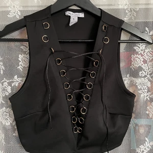 NLY crop top - Snygg Crop top med snöring från Nelly, den är i rätt fint skick (köpt begagnad). Den är strechig. Katt finns i hemmet. Köparen står för frakten, kan även mötas upp i Uddevalla.  