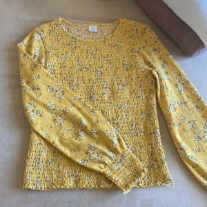 Lindex  - En gul,blommig topp i storlek 158/164,passar för 12-14 åringar,köpte den för drygt en månad sen och använd 2-3 gånger