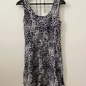 Leopardmönstrad klänning i vitt och mörkblått. U-ringad och med tunnt resor i midjan. 