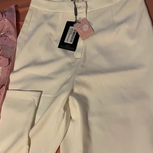 Gräddvita Kostymbyxor - Säljer mina helt oanvända gräddvita kostymbyxor från prettylittlething i storlek 38 som motsvarar S men passar M också. Säljer dessa då dom var ganska långa och pösiga vid benen då jag är 152. 