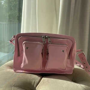 Rosa Nunoo  - Säljer min fina Nunoo väska i rosa som tyvärr aldig kommit till användning. Nypris ligger på 1899kr. Långt band medföljer också. Rymlig väska med många fack och utrymmen perfekt till skolan/jobbet. Vid leverans står köparen för kostanden. 