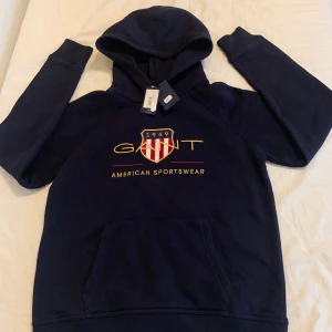 Gant Hoodie - 170 cm/15y - Helt ny, oanvänd mörkblå Gant hoodie med tags. Ny pris 899 kr. Säljs pågrund av att den är för liten. Möts i Årstaberg/Stockholm. För fler bilder kom dm. Kan fraktas men kund står för det.