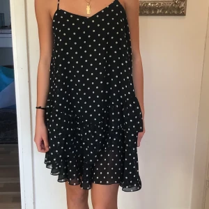 Svartvit prickig klänning med volanger.  - Svartvit prickig klänning med volanger. Använd 1 gång. Justerbara band och banden korsar sig i ryggen. Storlek 34. Passar mig som har xs och xxs. 🌸 Buda här på Plick fast privat. Kan tänka mig att gå ner i pris vid snabb affär 🌸