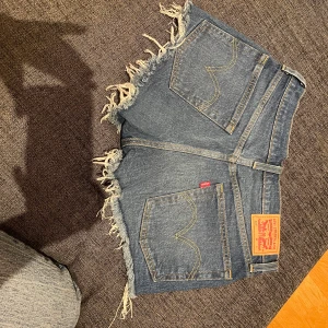 Blåa Levis shorts 501 i storlek W 25 (S) - Jag säljer mina oanvända Levis shorts. tyvärr är prislappen inte kvar då jag tar bort de när jag lägger in plagg i min garderob. W 25 skulle säga att de sitter som en s. Köparen står för frakt men kan tänka mig oxå mötas upp i Kungälv.