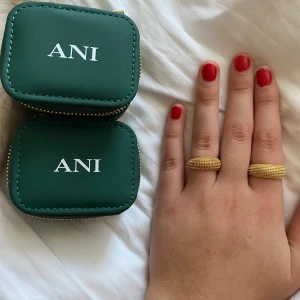 ANI guldring - Ringen är ett örhänge från ANI som gått sönder, pinnen har gått av. Kan därför användas som ring. På första bilden ser man till vänster örhänget och till höger den riktiga guld ringen från ANI. Örhänget nypris 1100, riktig ring nypris 600 kr. En Ask ingår