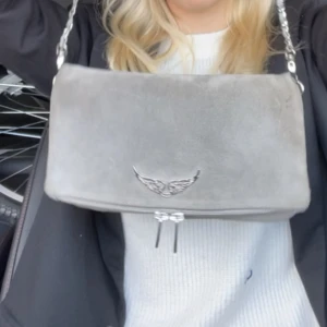 Zadig & Voltaire  - Säljer en zadig & voltaire väska i mellan storleken. Grå mocha material. Använd ganska mycket men fint skick. Långt & kort band följer med. Lånade bilder