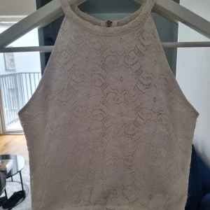Topp - En vit spetstopp från Bikbok. Den är typ en polomodell och har en spetskant längst ner. Sitter jättefint och är bekväm.