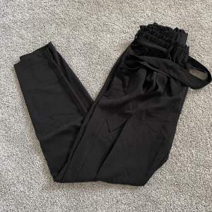 Svarta kostymbyxor med snörning i midjan från BikBok. Storlek S