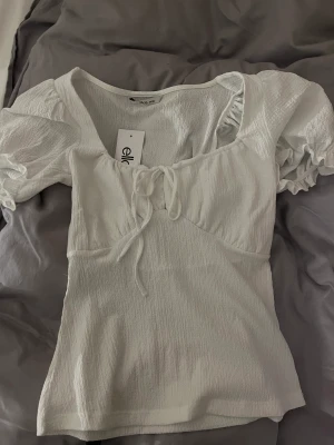 Fin somrig topp - Jättefin helt ny topp, perfekt till sommaren! Aldrig använd, endast testad, lappen kvar och allt. Puffärmar och utsvängd nertill. Från Ellos, strl 34/36 (minsta storleken). Säljer för 219kr.