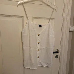 Linne från Gina Tricot  - Säljer denna söta linne från Gina Tricot. Helt ny med prislapp kvar. Storlek 44. 100% viskos. Knappar framtill och reglerbara band.
