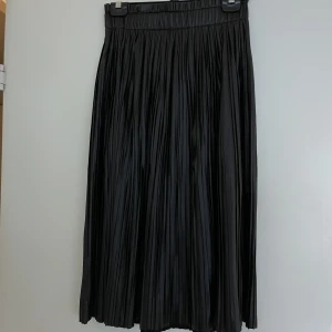 Kjol strl S - Superfin plisserad kjol i skinnimitation. Resår i midjan. Storlek S från Only, Vero Moda. Oanvänd med lappen kvar (nypris 529:-).  Mått:  Midja 35cm Längd 76cm