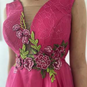 En ceriserosa klänning som är kortare fram (till knäna) och längre baktill med släp. Underdelen har volanger med tyg som skapar volym i klänningen.   Klänningen är använd enbart 1 gång och säljs pga platsbrist. 