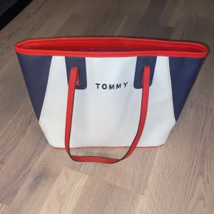 Tommy Hilfiger väska  - En fin Tommy Hilfiger väska som jag tyvär inte har någon användning för längre. Den är använd ett fåtal gånger och den har ett stort mittenfack som man kan stänga. Den är inte äkta.