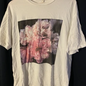 T-shirt med tryck - T-shirt med blommigt tryck. Som man ser bättre på andra bilden så har den ett litet hål precis över trycket. - passar Xs - L 🌸köper du denna kan du även få den andra blommiga t-shirten jag säljer (2för1 alltså)🌸