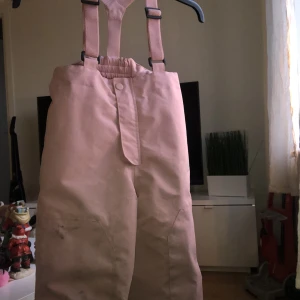 Fodrade regnbyxor - Rosa fodrade regnbyxor, med hängslen och hög midja. (Täckbyxa liknande)  Storlek 104.  Tvättas såklart innan dom skickas.  