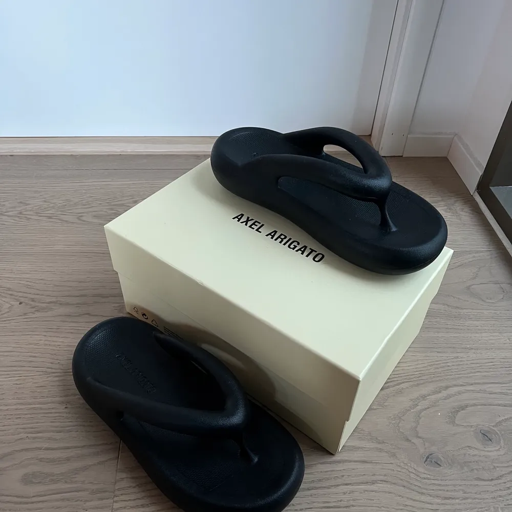 Säljer mina helt oanvända flipflops från axel arigato. Strl 40. Kartong följer med också. Köpta för 1100kr.  Köparen står för frakten. . Skor.