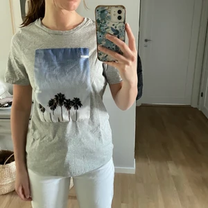 T-shirt - Grå skön T-shirt med en himmel och några palmer på som bara har använts väldigt få gånger😍🌴