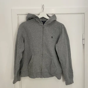 Polo Ralph Lauren Zip Hoodie - Säljer nu min gråa Polo Ralph Lauren Zip Hoodie då den är för liten. Den är i storlek 14-16 år vilket motsvarar ungefär XS-S! Den är i väldigt gott skick! Kan mötas upp i Göteborg eller frakta!!