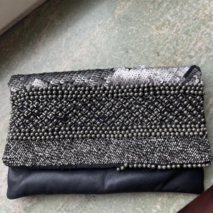 Twist & tango clutch - Twist & tango clutch inköpt på deras butik i Göteborg. Har gått sönder längst ner, se bild. Men går absolut att använda ändå och om man är pillig, är det lätt fixat.   Den är väldigt rymlig och man får med sig allt man kan tänka sig på en utekväll! 