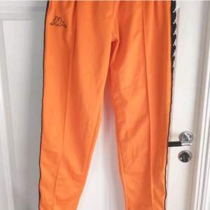 Orangea byxor från Kappa med gömd snörning i midjan och knappar längs benen. Dom är i storlek XL men passar perfekt på mig som är M.