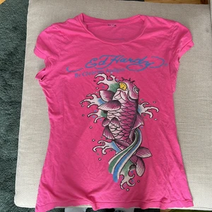 Cool Ed Hardy t-shirt - Snygg ed Hardy T-shirt som är min mammas gamla. Har inte använt så mycket så tänkte sälja den❤️ har ett litet hål vid armhålan men de är inte som man märker. Säljer för 200 men priset kan diskuteras🫶🏻