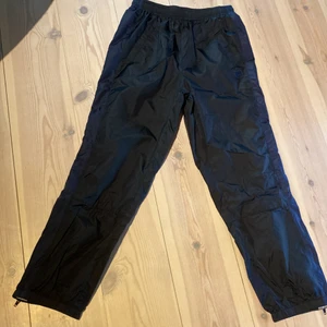 Svartblåa Acne Studios Striped track pants - Jag säljer mina svarta Acne studios med kontrast av blå på sidorna track byxor. Med Acnes kända loggo på ena sidan. De är i Nylon. Skriv för frågor eller fler bilder. Storlek XS men är stora i storleken. Nypris: 2500kr